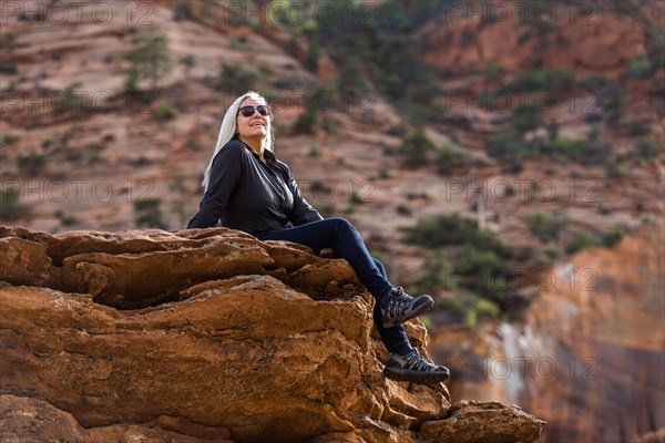 Caucasian woman sitting on edge of rock