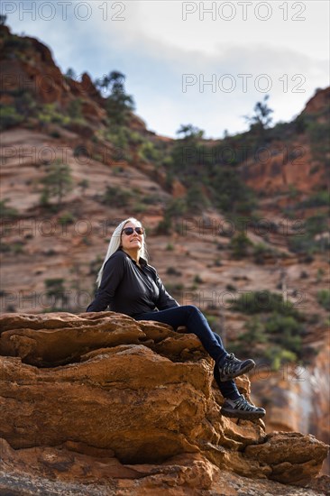 Caucasian woman sitting on edge of rock