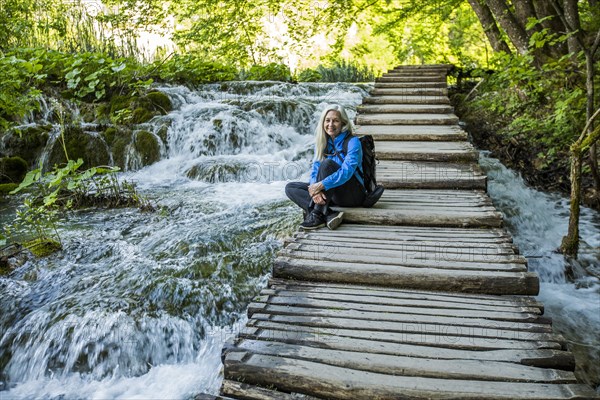 Older Caucasian woman sitting on wooden staircase over waterfalls