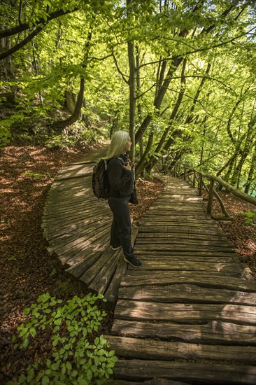 Older Caucasian woman walking on wooden pathway in forest