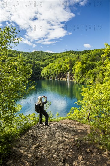 Older Caucasian woman photographing waterfall with cell phone