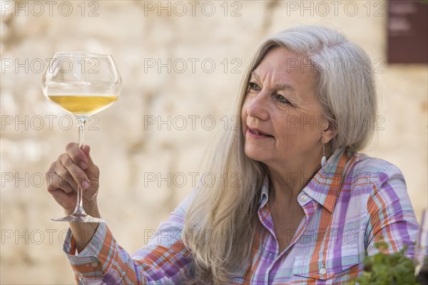 Older Caucasian woman examining white wine