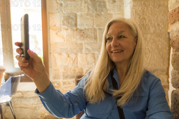 Older Caucasian woman posing for cell phone selfie