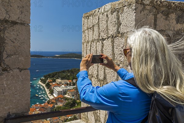 Caucasian woman photographing scenic view of ocean