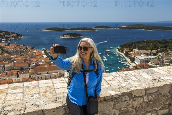 Caucasian woman posing for cell phone selfie with scenic view of ocean