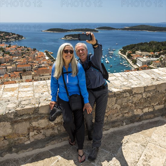 Caucasian couple posing for cell phone selfie with scenic view of ocean