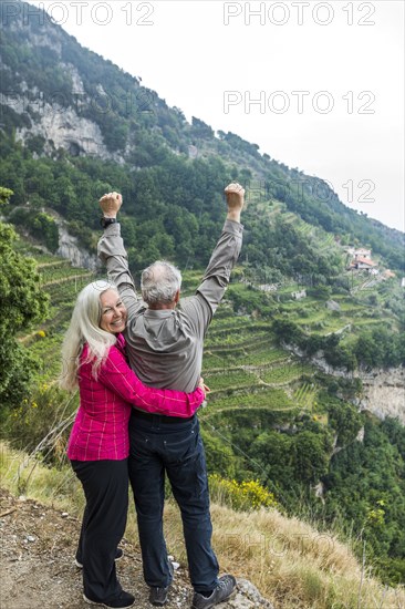 Caucasian couple celebrating on hill