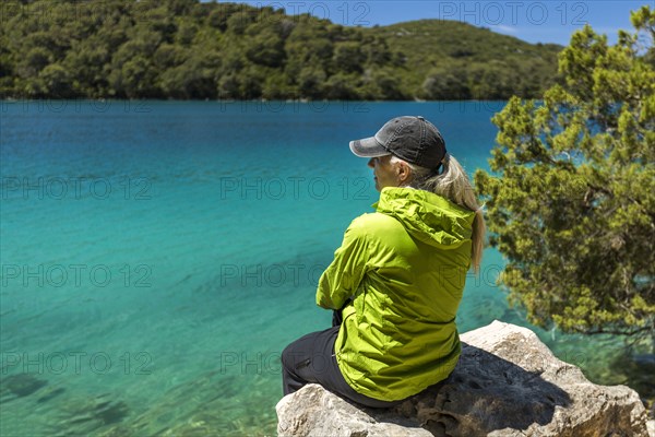 Caucasian woman sitting on rock at lake
