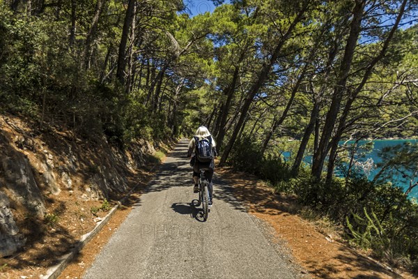 Caucasian woman riding bicycle on path near lake