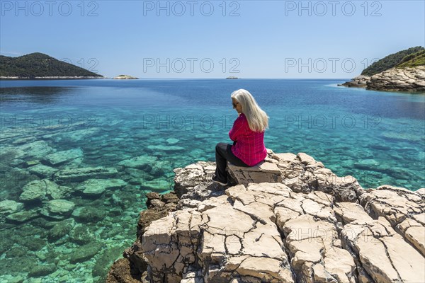 Caucasian woman sitting on rock admiring lake