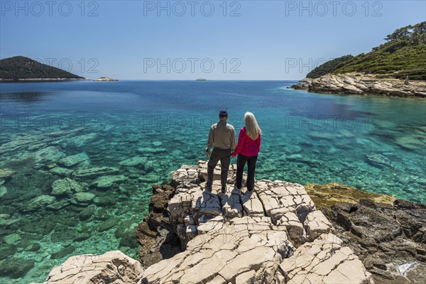 Caucasian couple standing on rock admiring lake