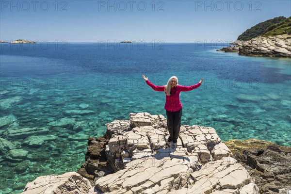 Caucasian woman posing on rock at lake