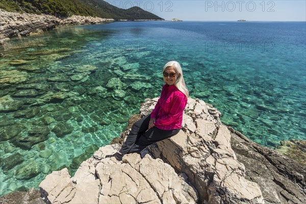 Caucasian woman posing on rock at lake