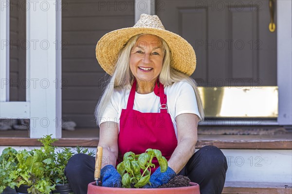 Caucasian woman planting seedling on front stoop