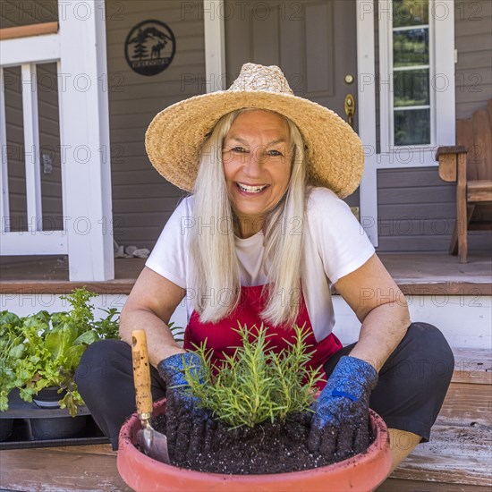 Caucasian woman planting seedling on front stoop