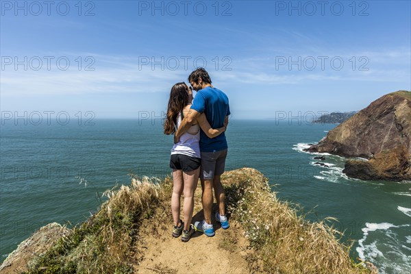 Couple hugging near scenic view of ocean