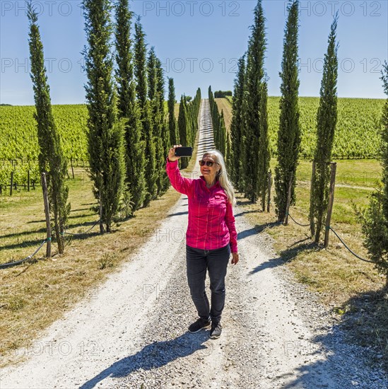 Caucasian woman posing for cell phone selfie on dirt road