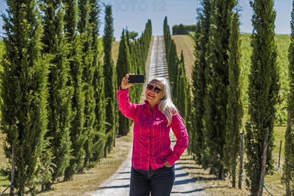 Caucasian woman posing for cell phone selfie on dirt road