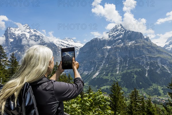 Caucasian woman photographing mountain with digital tablet