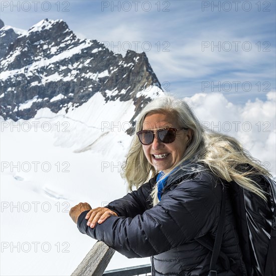 Portrait of smiling Caucasian woman leaning on railing near mountains