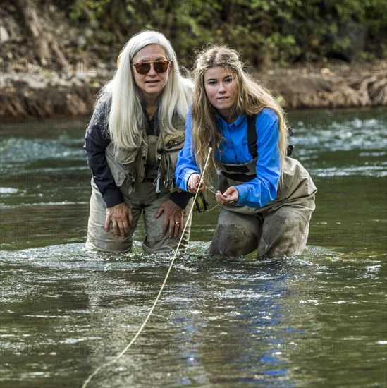 Caucasian mother and daughter fly fishing