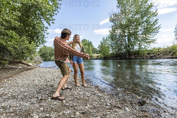 Caucasian couple skipping stones in river