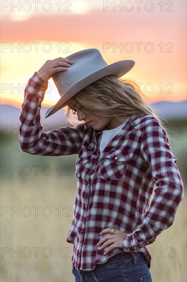 Caucasian teenage girl wearing cowboy hat at sunset