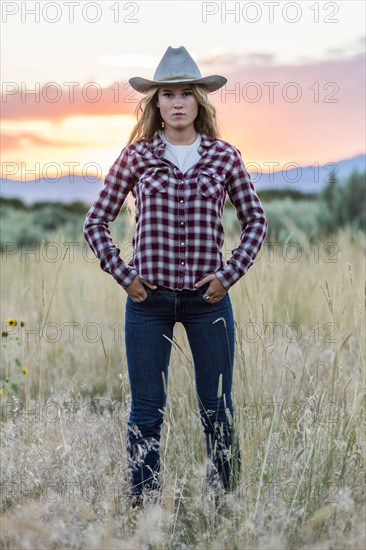 Portrait of serious Caucasian teenage girl wearing cowboy hat at sunset