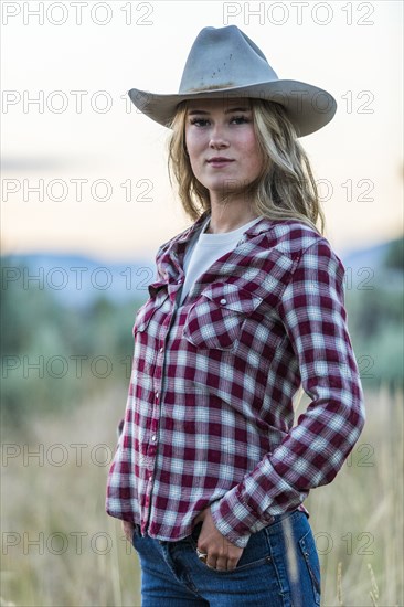 Portrait of smiling Caucasian teenage girl wearing cowboy hat at sunset