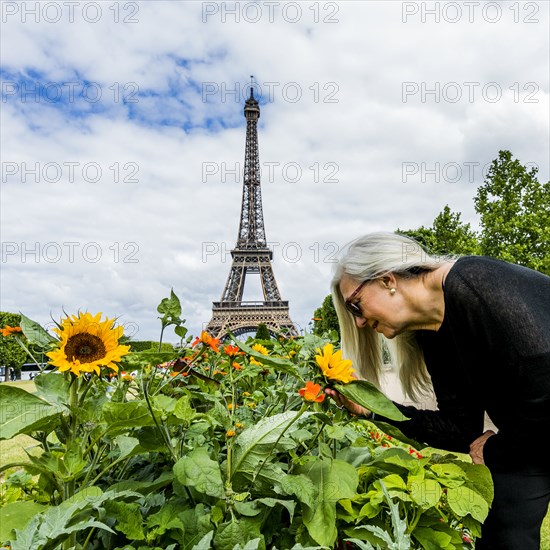 Caucasian woman smelling flowers near Eiffel Tower