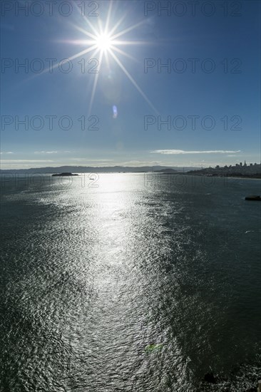 Sunbeams in blue sky over bay