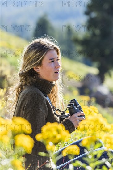 Caucasian girl in field holding binoculars