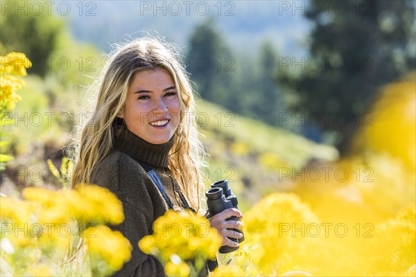 Caucasian girl in field holding binoculars