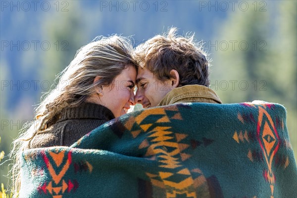 Caucasian couple wrapped in blanket rubbing noses