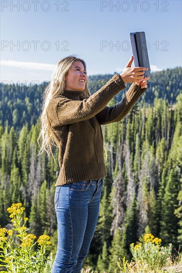 Caucasian girl photographing landscape with digital tablet