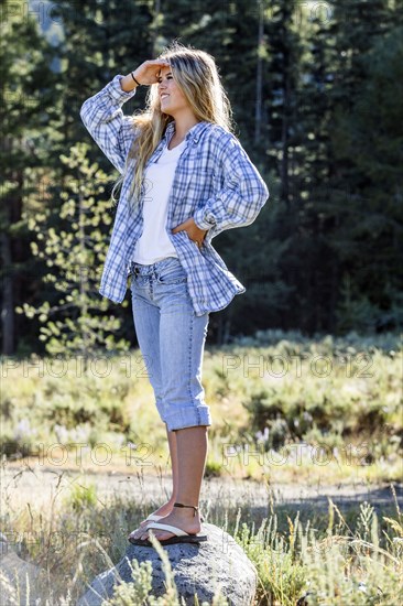 Caucasian girl wearing plaid shirt standing on rock