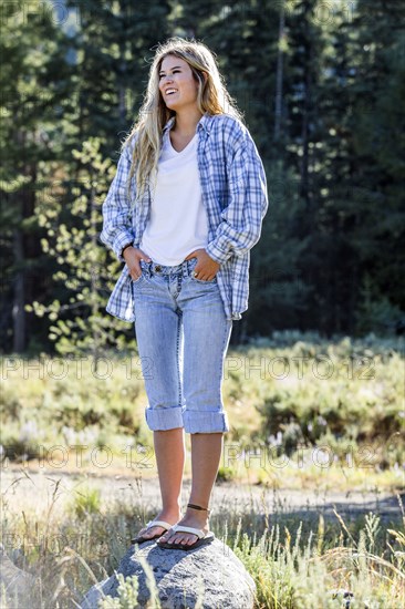 Caucasian girl wearing plaid shirt standing on rock