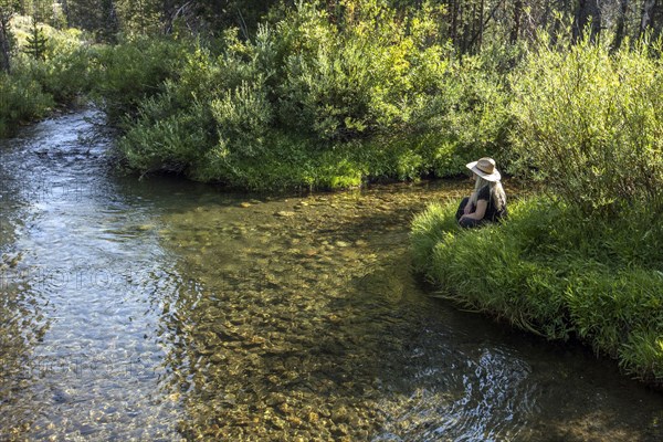 Caucasian woman sitting near tranquil river