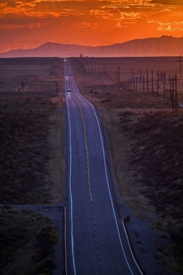 Cars driving on remote road at sunset