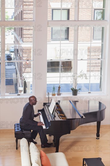 Man playing piano near window