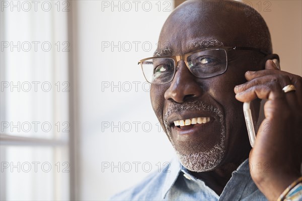 Man talking on cell phone near window
