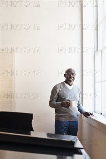Man drinking coffee near window