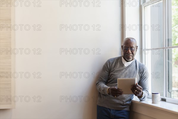 Man using digital tablet near window