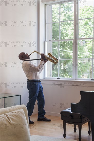 Man playing saxophone near window