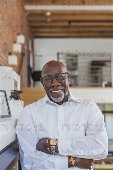 Smiling man with arms crossed leaning on mantle
