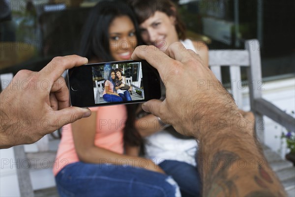 Man photographing women with cell phone