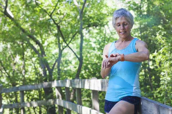 Caucasian woman leaning on wooden fence checking the time