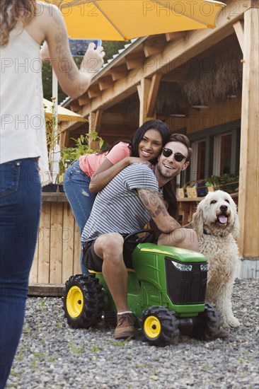 Woman photographing couple and dog with cell phone