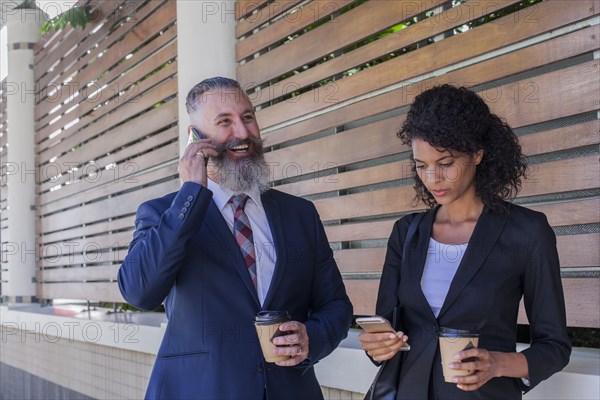 Business people standing outdoors using cell phones