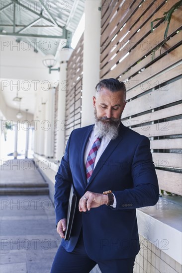 Caucasian businessman on sidewalk checking the time on wristwatch